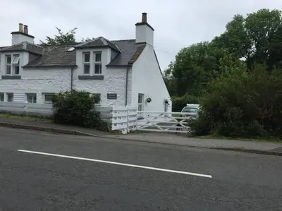 a white house on the side of a road at Bridgend Cottage, Auchencairn, Castle Douglas in Auchencairn