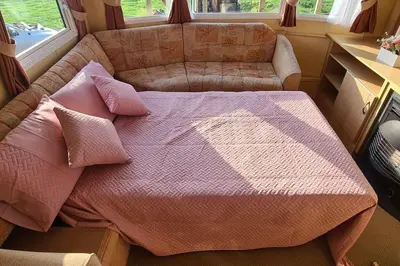 a bed with pillows and a couch in a room at Tarn Bay Retreat- Sea- Fells- Beach- Views-Farm in Millom