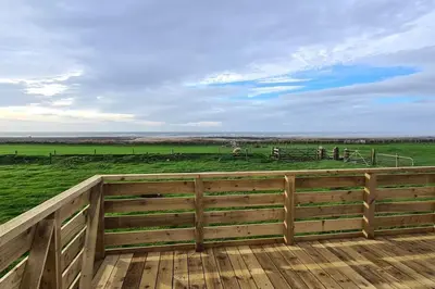 a wooden fence with a horse in a field at Tarn Bay Retreat- Sea- Fells- Beach- Views-Farm in Millom
