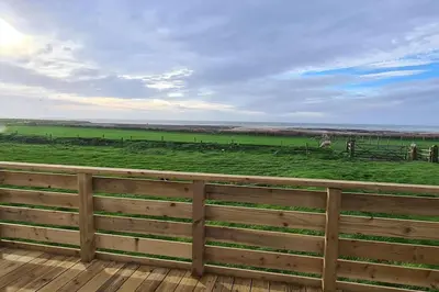 a wooden fence with a view of a green field at Tarn Bay Retreat- Sea- Fells- Beach- Views-Farm in Millom