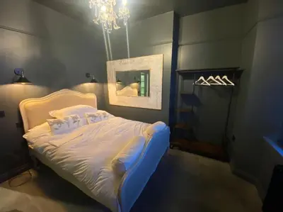 a bedroom with a bed with a painting and a chandelier at Kirkcudbright 3 bed ultra modern brand new in Kirkcudbright