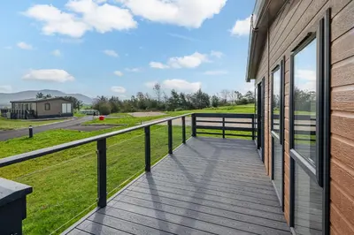 a wooden deck on the side of a house at Oak Tree Timber Holiday Lodge in Bassenthwaite
