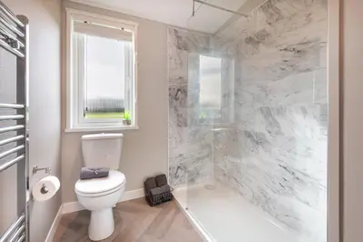 a bathroom with a toilet and a shower and a window at Oak Tree Timber Holiday Lodge in Bassenthwaite