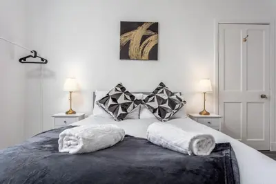 a bedroom with a white bed with two lamps at Berelands House - Donnini Apartments in Prestwick