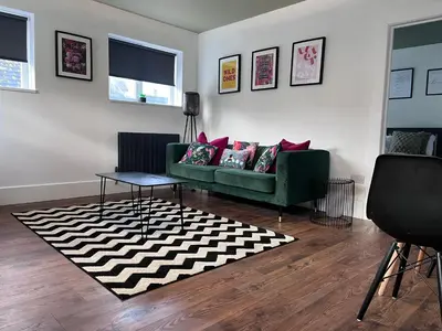 a living room with a green couch and a black and white rug at The Boyd - Coorie Doon in Prestwick