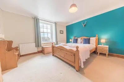 a bedroom with a bed and a blue wall at Historic St Bees Farmhouse Hot Tub Games Summer Gatherings in St Bees