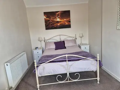 a bedroom with a bed with purple sheets and a painting on the wall at RAWSON COTTAGE LOVELY 2 BEDROOM SEMI RURAL in Stranraer