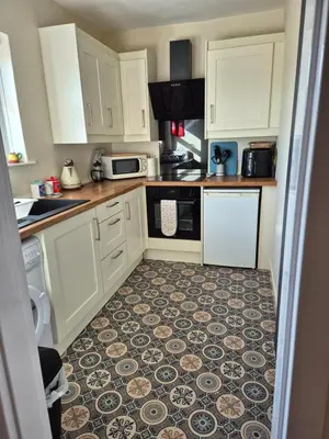 a kitchen with white cabinets and a tile floor at RAWSON COTTAGE LOVELY 2 BEDROOM SEMI RURAL in Stranraer