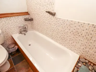 a bath tub in a bathroom with a toilet at Beck Edge in Keswick