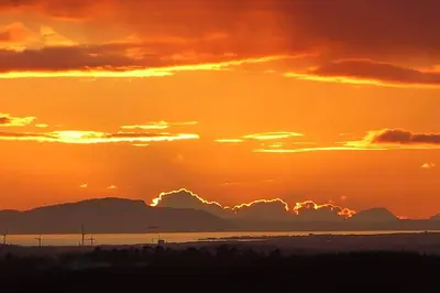 a sunset over the water with mountains in the background at Blackside Cottage - A Luxury Rural Retreat in Mauchline
