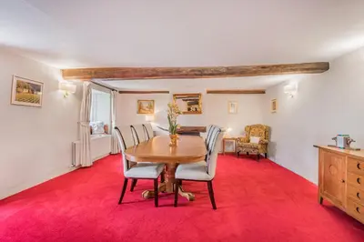 a dining room with a table and chairs on a red carpet at farmhouse braithwaite mews in Keswick