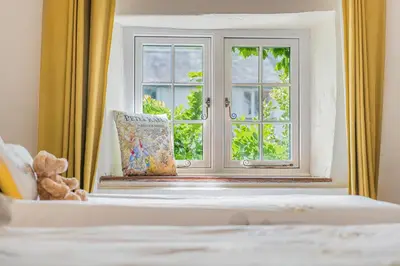 a bed with a window and a teddy bear next to it at farmhouse braithwaite mews in Keswick