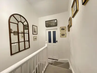 a white hallway with a white door and pictures on the wall at Spa Cottage in Braithwaite