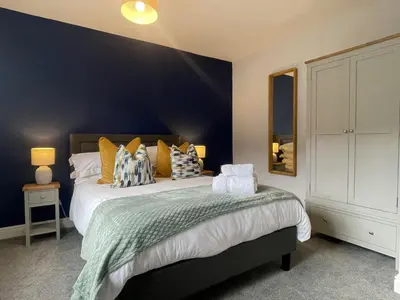 a bedroom with a large bed and a blue wall at Red Robin in Keswick