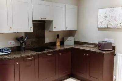 a kitchen with white cabinets and a counter top at Grey Walls in Penrith