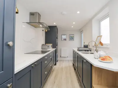 a kitchen with blue cabinets and white counter tops at Forty Five in Keswick