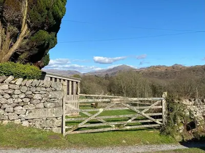 a wooden gate in a field with a stone wall at Hillside Cottage Eskdale Green in Beckfoot