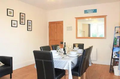 a dining room with a table with black chairs at Hillside Cottage Eskdale Green in Beckfoot