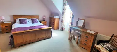 a bedroom with a bed and a dresser and a desk at Glenterry Farmhouse in Kirkcudbright