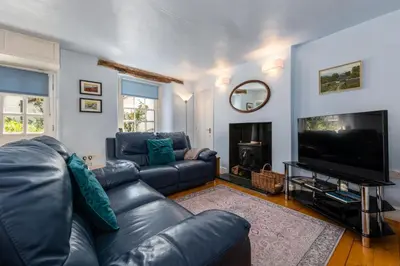 a living room with a leather couch and a flat screen tv at Bridge Cottage Keswick in Keswick