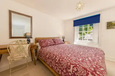 a bedroom with a bed and a desk and a mirror at Bridge Cottage Keswick in Keswick