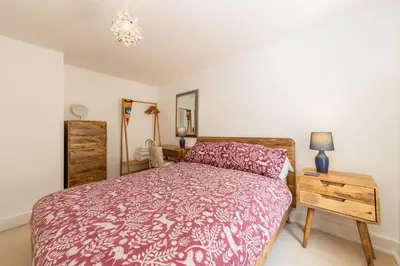 a bedroom with a bed and a dresser and a mirror at Bridge Cottage Keswick in Keswick