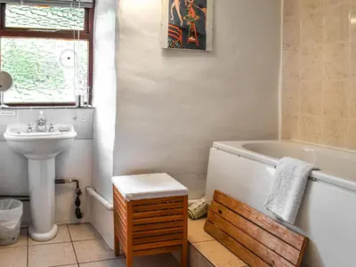 a bathroom with a tub and a sink at Church House Cottage in Ulpha