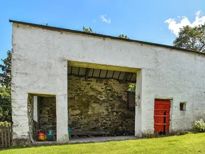 a white brick building with a red door and a yard at Church House Cottage in Ulpha