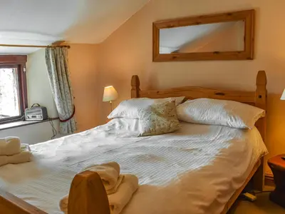 a bedroom with a large white bed and a mirror at Church House Cottage in Ulpha