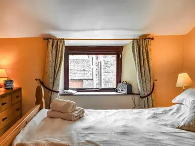 a bedroom with a bed and a window at Church House Cottage in Ulpha