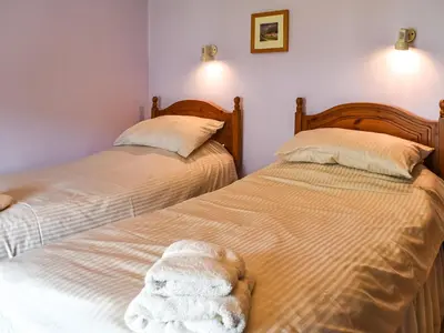 two beds sitting next to each other in a bedroom at Church House Cottage in Ulpha