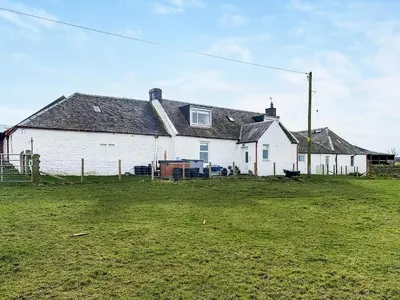 a white house with a grass field in front of it at Muirston Farmhouse - Uk44977 in Ayr