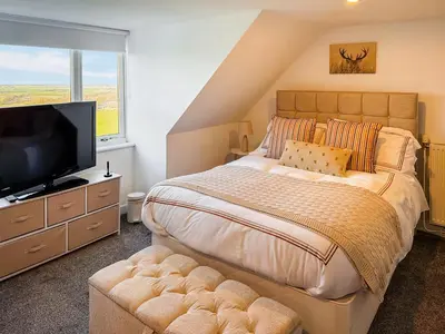 a bedroom with a large bed and a flat screen tv at Muirston Farmhouse - Uk44977 in Ayr