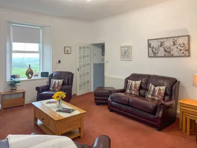 a living room with two leather chairs and a coffee table at Muirston Farmhouse - Uk44977 in Ayr