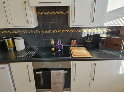 a kitchen with white cabinets and a black counter top at Carlisle City Centre. Spacious Apartment. Ideal location. in Carlisle