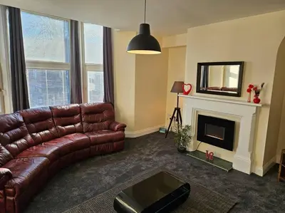 a living room with a leather couch and a fireplace at Carlisle City Centre. Spacious Apartment. Ideal location. in Carlisle