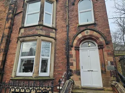 a brick building with a white door and windows at Carlisle City Centre. Spacious Apartment. Ideal location. in Carlisle