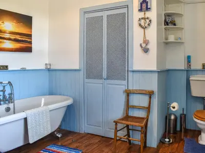 a blue bathroom with a tub and a chair at Harebeck Cottage in Gosforth