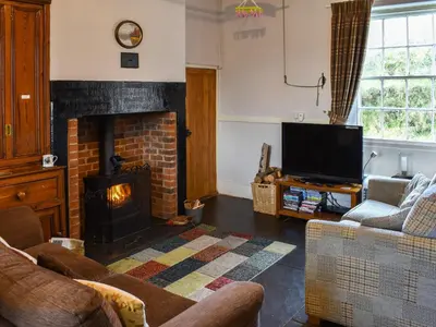a living room with a fireplace and a tv at Harebeck Cottage in Gosforth