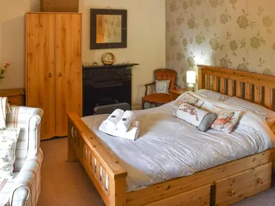 a bedroom with a large wooden bed and a fireplace at Harebeck Cottage in Gosforth