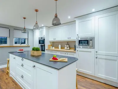 a kitchen with white cabinets and a black counter top at 3 Bed in Bridekirk 85717 in Bridekirk