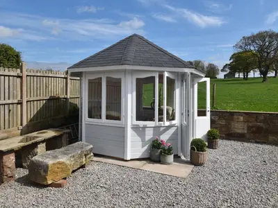 a white gazebo with a bench and a fence at 3 Bed in Bridekirk 85717 in Bridekirk