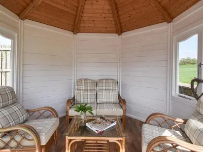 a screened in porch with two chairs and a table at 3 Bed in Bridekirk 85717 in Bridekirk