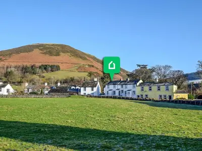 a hill with a green sign in front of houses at 2 Bed in High Lorton 86023 in Lorton