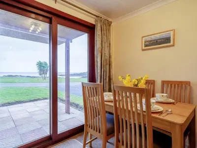 a dining room with a table and a sliding glass door at 2 Bed in Isle of Whithorn 77880 in Isle of Whithorn