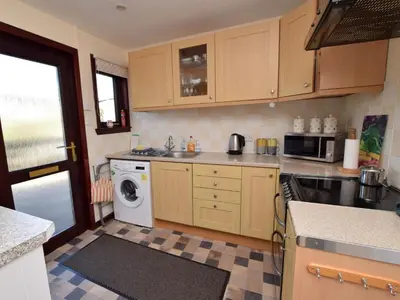 a kitchen with wooden cabinets and a washer and dryer at 2 Bed in Isle of Whithorn 77880 in Isle of Whithorn