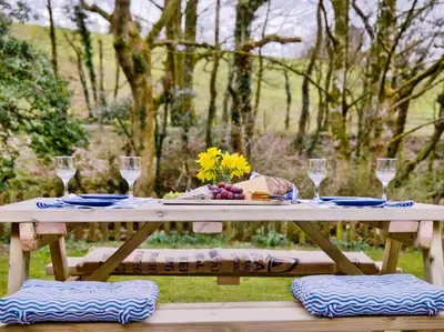 a picnic table with wine glasses and flowers on it at 3 Bed in Ennerdale Bridge SZ392 in Ennerdale Bridge