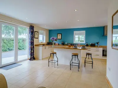 a kitchen with three bar stools and a counter at 1 Bed in Grinsdale Bridge 85163 in Carlisle
