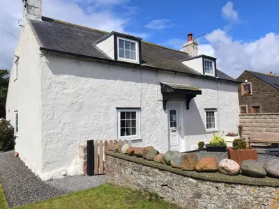 a white house with rocks in front of it at 2 Bed in Mawbray SZ214 in Mawbray