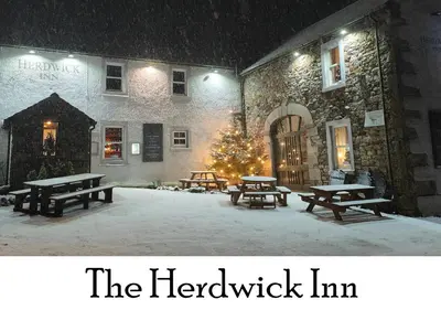 a group of picnic tables in the snow in front of a building at The Herdwick Inn in Penruddock